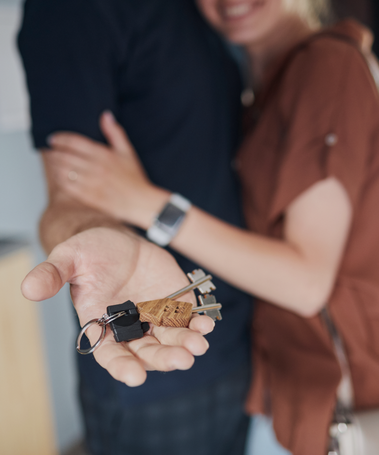 A happy couple holding house keys, celebrating their new home.