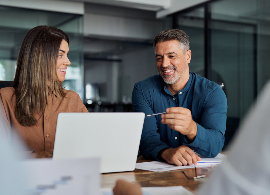A group of smiling business people collaborating and looking at a laptop screen.