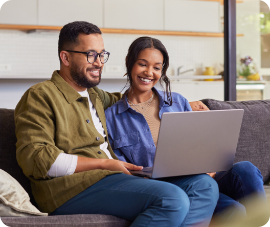 Happy couple browsing online with laptop while relaxing on sofa